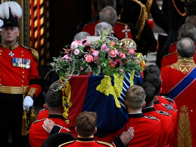 The coffin of Queen Elizabeth II with the Imperial State Crown resting on top is carried by the Bearer Party into Westminster Abbey