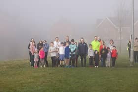A group of young children and parents standing ready to start the junior parkrun
