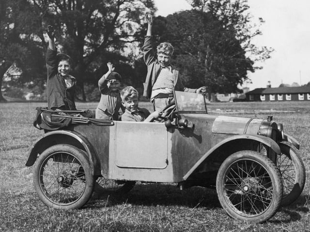 Two young boys drive their friends round a field in an Austin Seven car from their father's garage in Titchmarsh, Kettering. (Photo by Fox Photos/Getty Images)