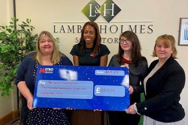 Lorraine Lewis receiving the donation from some of the team at Lamb & Holmes.