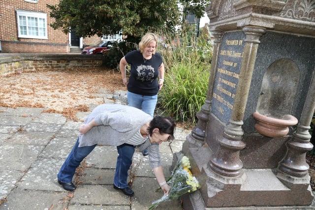 Sisters Mandy Fletcher and Kerri Blackwell place flowers at the Swanspool fountain in Wellingborough, in remembrance of The Queen