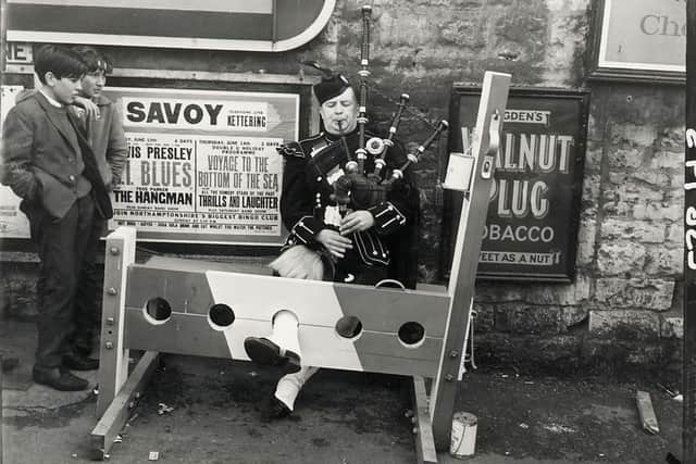 A piper in the stocks plays the bagpipes at the 1962 Corby Pole Fair