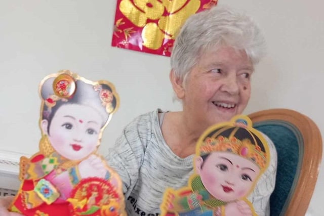 All smiles from one resident who is holding paper dolls.
