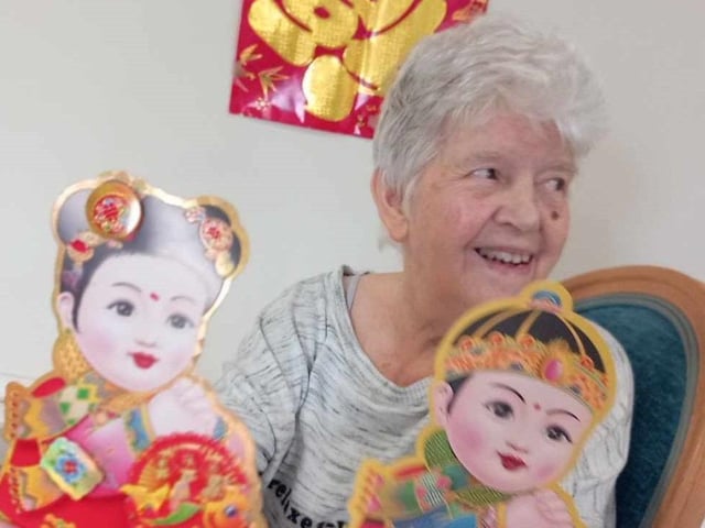 All smiles from one resident who is holding paper dolls.