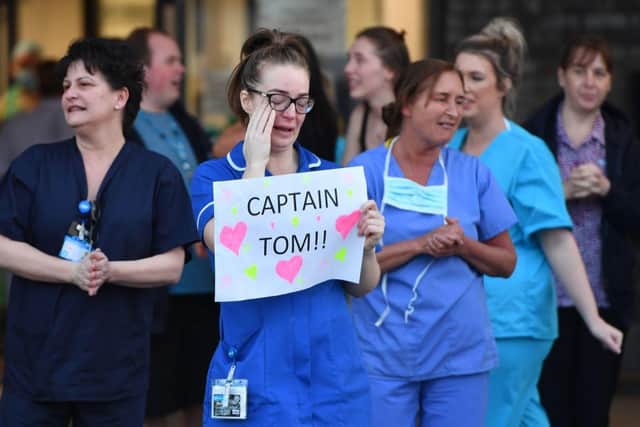 An NHS staff member wipes her eyes as she holds a sign to thank British veteran Captain Tom Moore who raised over £13 million for the NHS (Photo: ANTHONY DEVLIN/AFP via Getty Images)