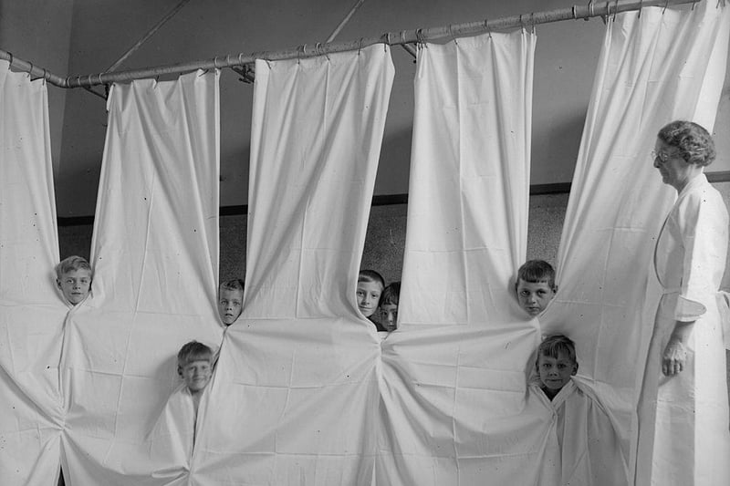 Young boys peering through cubicle curtains at the Open Air Recovery School in Kettering in 1934.