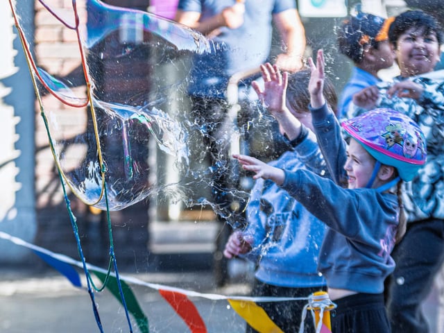 Kids chasing and popping the giant bubbles created by local bubble maestro ‘Just Karen’