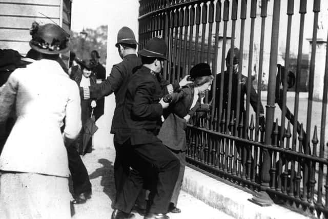 A policeman restrain a demonstrator as suffragettes gathered outside Buckingham Palace in 1914
