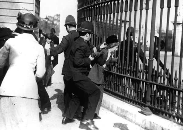 A policeman restrain a demonstrator as suffragettes gathered outside Buckingham Palace in 1914