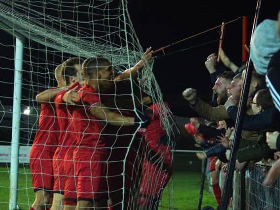 The Kettering Town players and fans celebrate Aaron O'Connor's late winner as they came from 3-2 down to beat 10-man Dorchester Town 4-3 at Latimer Park. Pictures by Peter Short