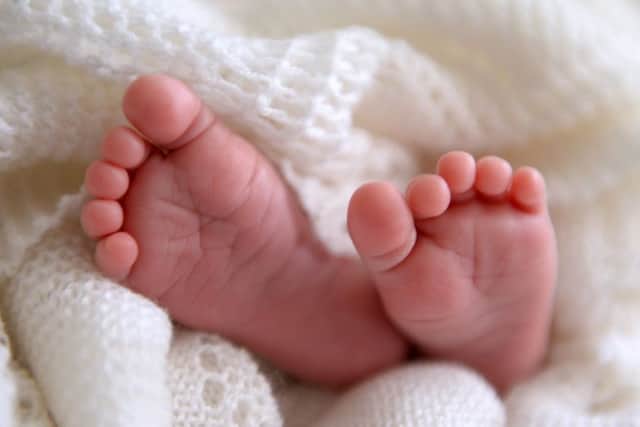 A new born baby's feet are visible peeking out of a shawl AJM_BABYSTOCK_05.jpg