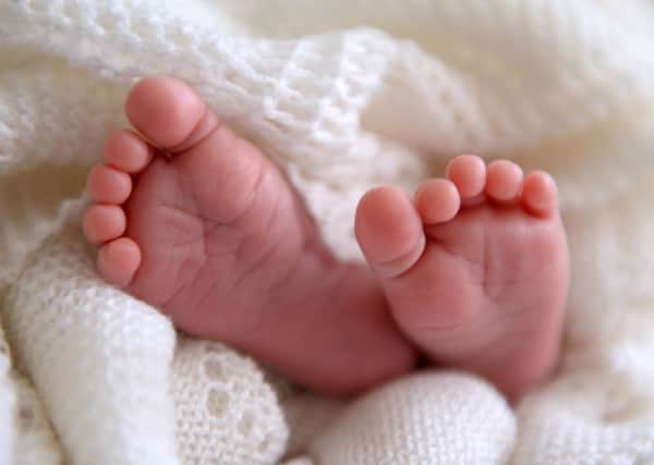 A new born baby's feet are visible peeking out of a shawl AJM_BABYSTOCK_05.jpg