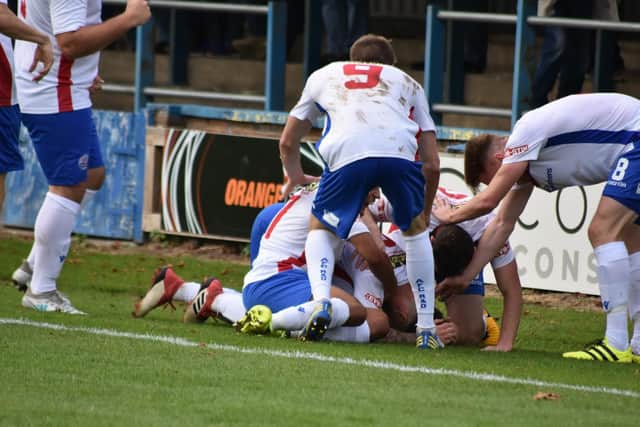 Declan Rogers is buried under of a pile of his AFC Rushden & Diamonds team-mates after he put them in front in the 1-1 draw at King's Lynn Town. Picture courtesy of HawkinsImages