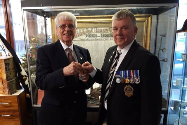 David (right) hands the medal over to Brian.