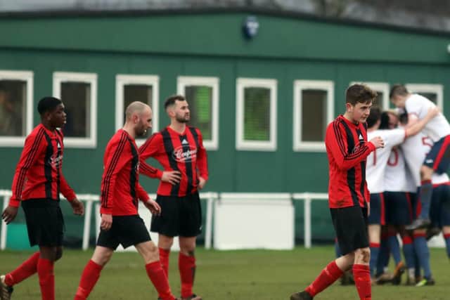 The Whitworth players look dejected while ON Chenecks celebrate one of their goals in the background. Chenecks claimed a 7-0 success in the United Counties League Premier Division clash. Pictures by Alison Bagley