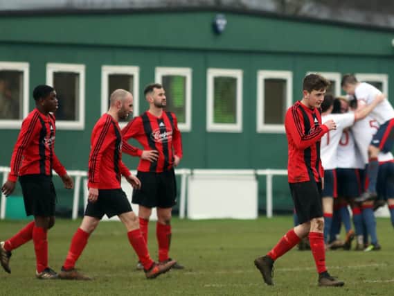 The Whitworth players look dejected while ON Chenecks celebrate one of their goals in the background. Chenecks claimed a 7-0 success in the United Counties League Premier Division clash. Pictures by Alison Bagley