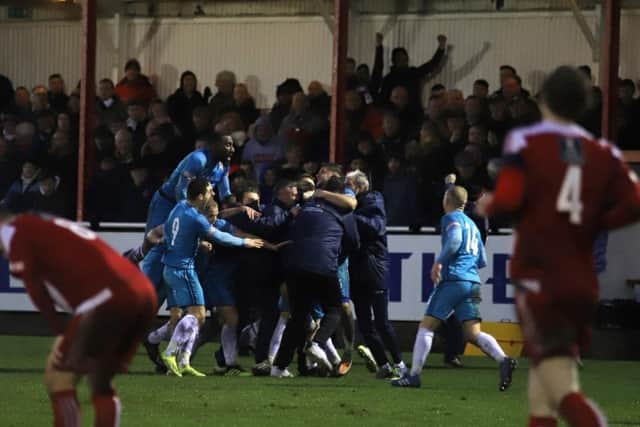 Tom Knowles is mobbed by his Kettering Town team-mates after his late free-kick sealed a 2-1 victory at Stourbridge and sent the Poppies to the top of the league. Picture by Peter Short