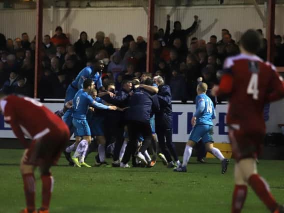 Tom Knowles is mobbed by his Kettering Town team-mates after his late free-kick sealed a 2-1 victory at Stourbridge and sent the Poppies to the top of the league. Picture by Peter Short