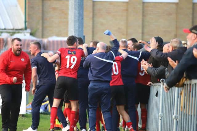 Aaron O'Connor is mobbed by players, staff and fans alike after his last-gasp goal gave Kettering Town a 1-0 win at Leiston and put them on the brink of the title. Pictures by Peter Short