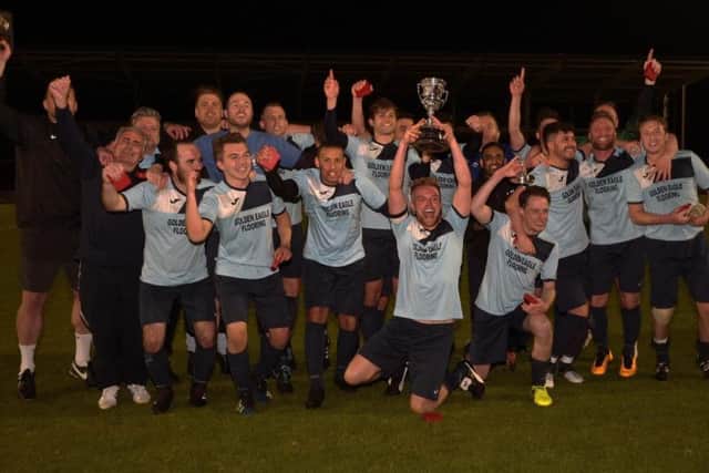 The Nomads players show off the Junior Cup on the Sixfields pitch
