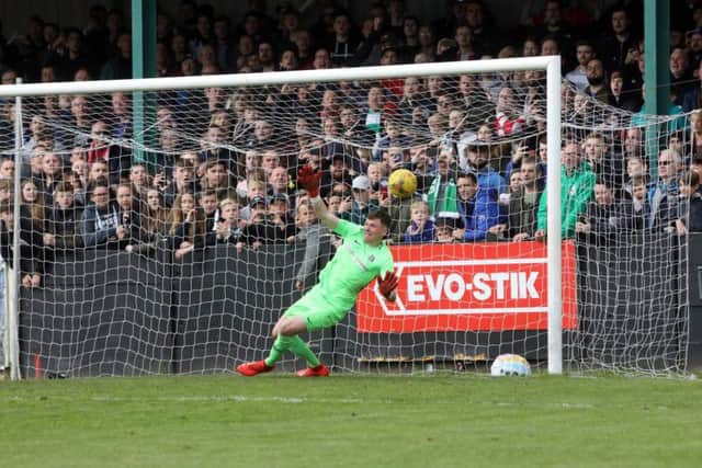 Corby goalkeeper Dan George makes the second of two penalty saves during the game