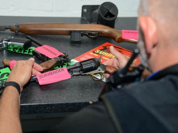 A police officer with some of the guns handed in during the amnesty so far. Photo: Northamptonshire Police