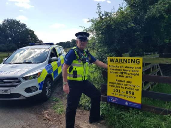 PCSO Les Conopo with the warning signs put up across Northamptonshire as a result of the sheep attacks. Photo: Northamptonshire Police