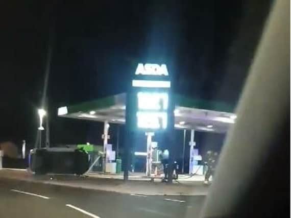 The car can be seen on its side to the left of the petrol station