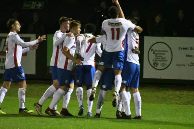 Jesse Akubuine is mobbed by his team-mates after his fine free-kick put Diamonds 2-0 against Corby