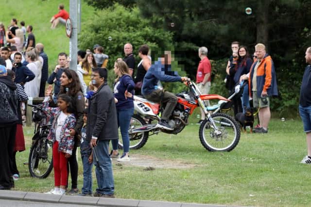 An off-road rider among crowds of people waiting to watch Corby Carnival