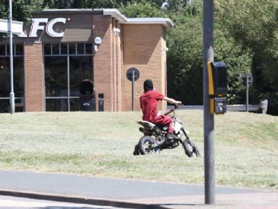 A nuisance motorcyclist rides on the grass outside KFC in Corby earlier this year