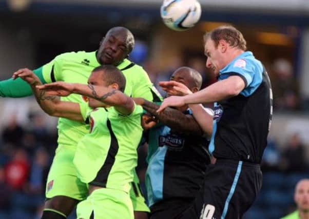 HEADS UP - Adebayo Akinfenwa and Clarke Carlisle battle fot the ball (Pictures: Kelly Cooper)
