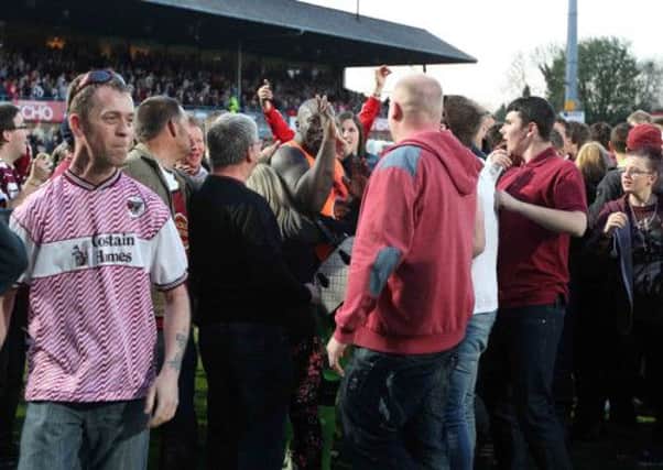 WEMBLEY WONDERLAND - Adebayo Akinfewna is swamped by Cobblers fans after the play-off victory at Cheltenham (pictures: Sharon Lucey/Kirsty Edmonds)