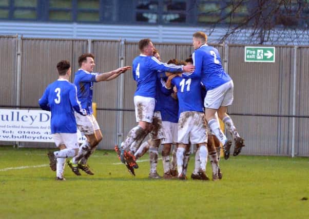Andy White is mobbed by his Rothwell Corinthians team-mates after scoring his and his team's second goal in last weekend's superb 2-1 win at Holbeach United. Picture by Tim Wilson
