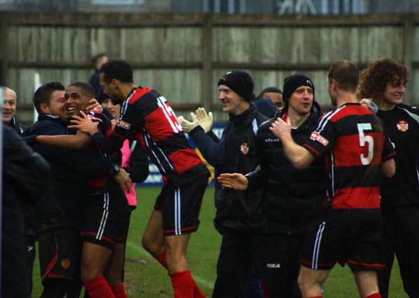 Wilson Carvalho is mobbed by the Kettering Town players and coaching staff after his late goal wrapped up the fine 2-0 victory at Chippenham Town. Pictures by Peter Short