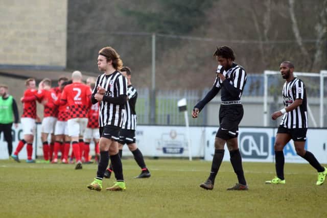 The Corby Town players show their disappointment while Nuneaton Town celebrate their third goal during the 3-1 win at Steel Park. Pictures by Alison Bagley