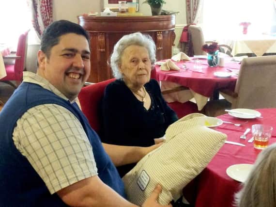 Chris Rayatt-Howard hands Joyce Beckett the cushion made from her late husband's shirt. Picture: SWNS