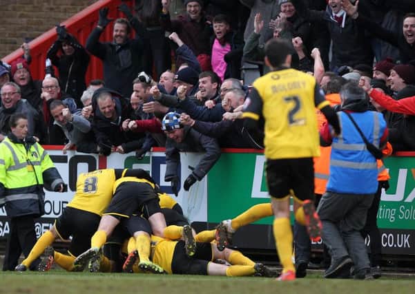 PILE ON! - the Cobblers players and supporters celebrate Ricky Holmes' late, late winner (Pictures: Sharon Lucey)