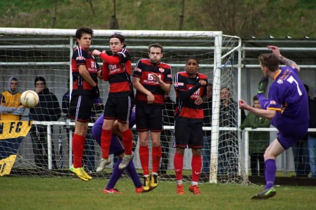 The Kettering Town wall jumps to block a free-kick in the clash with Slough Town