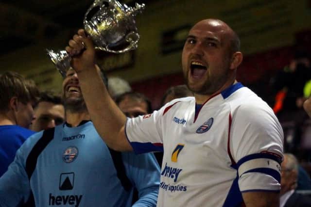AFC Rushden & Diamonds captain Liam Dolman lifts the NFA Hillier Senior Cup after the 2-1 success over Kettering Town