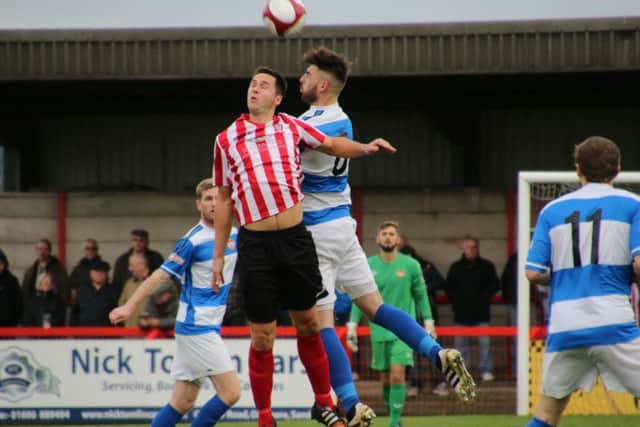 Paul Malone challenges for a high ball during the Poppies' loss at Witton