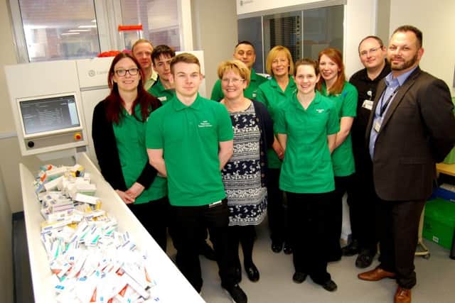 Some of the Pharmacy team beside the new Â£200,000 robot which sorts and dispenses items automatically