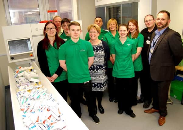 Some of the Pharmacy team beside the new Â£200,000 robot which sorts and dispenses items automatically
