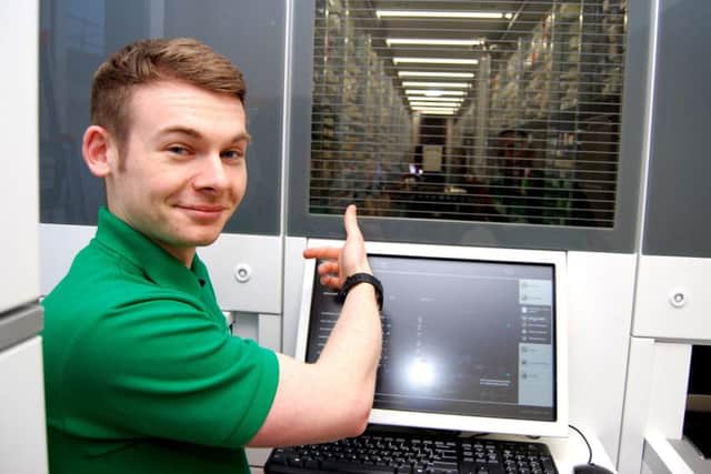 Pharmacy support technician James Maxwell points inside the pharmacy robot  inside it a robot arm is automatically selecting and dispensing medications to waiting ward boxes.