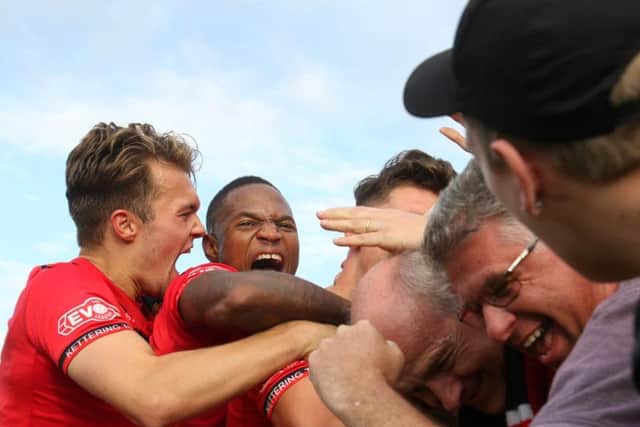 Mathew Stevens is buried under a pile of players and fans after putting 10-man Kettering Town 2-1 up against Chesham United. Pictures by Peter Short