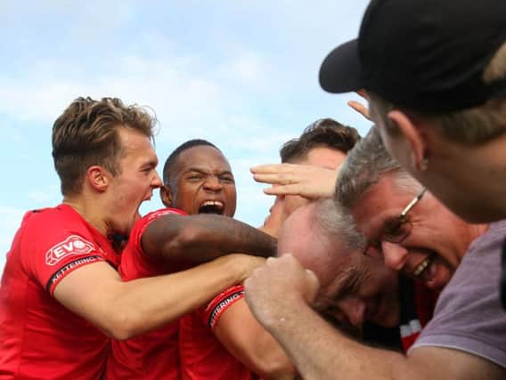 Mathew Stevens is buried under a pile of players and fans after putting 10-man Kettering Town 2-1 up against Chesham United. Pictures by Peter Short